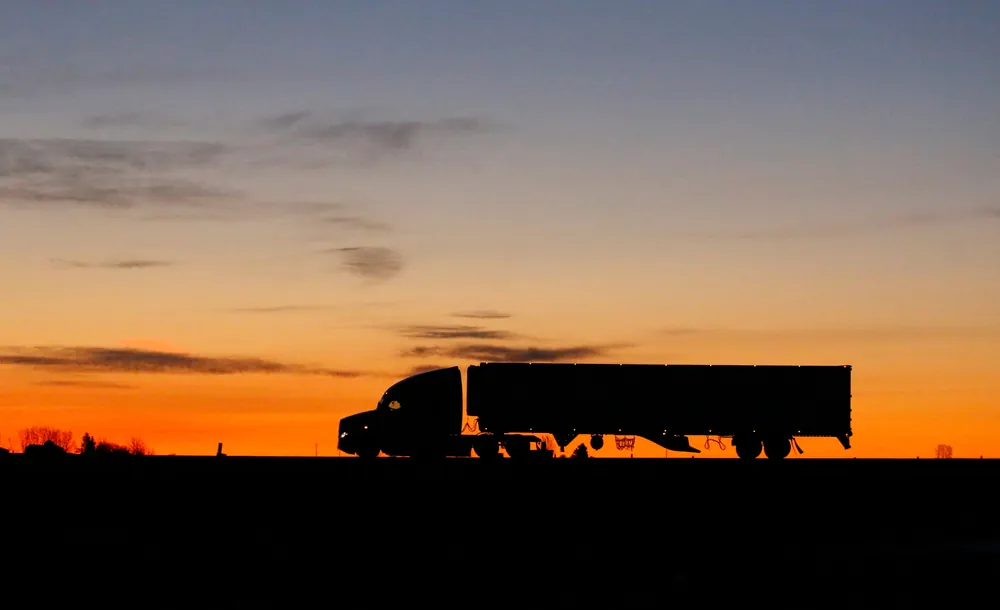 silhouette-of-a-large-truck-driving-on-a-road-at-2