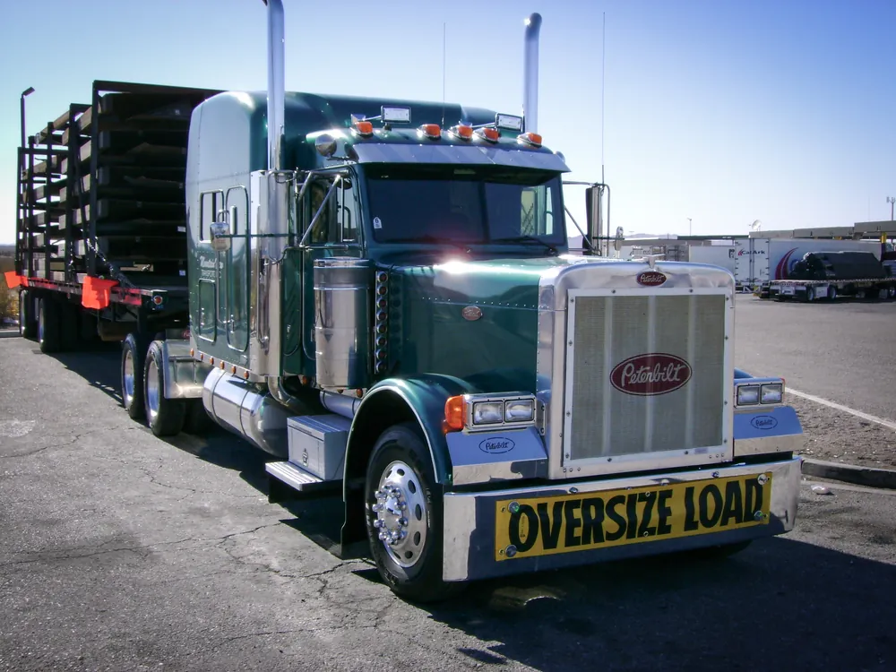 front of a semi truck with a oversize load banner sign on the front bumper