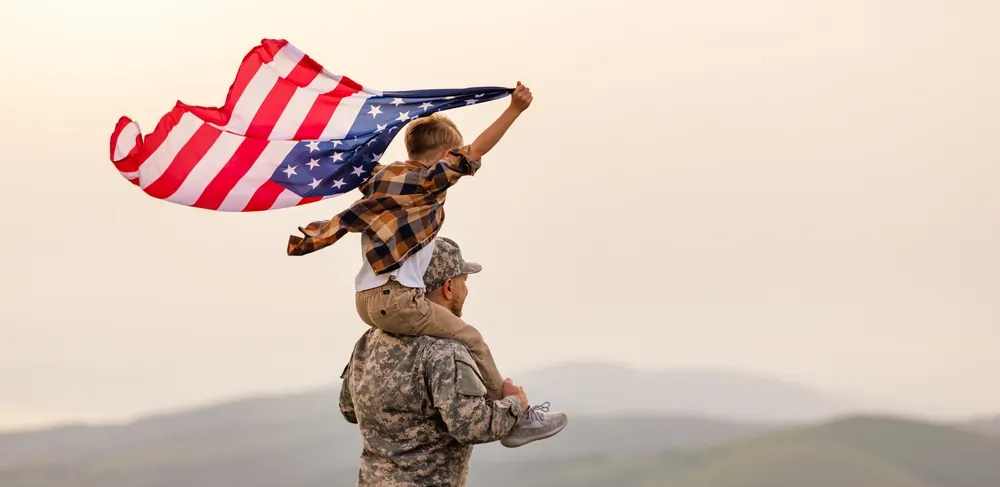 military man carrying son with flag