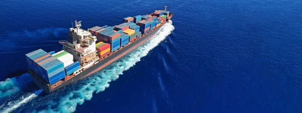 Aerial drone ultra wide top down photo of container cargo tanker ship carrying truck-size colourful containers in deep blue open ocean sea