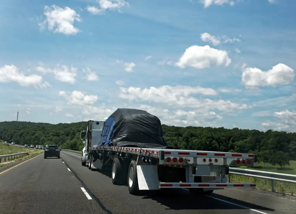 Flatbed semi transporting covered freight