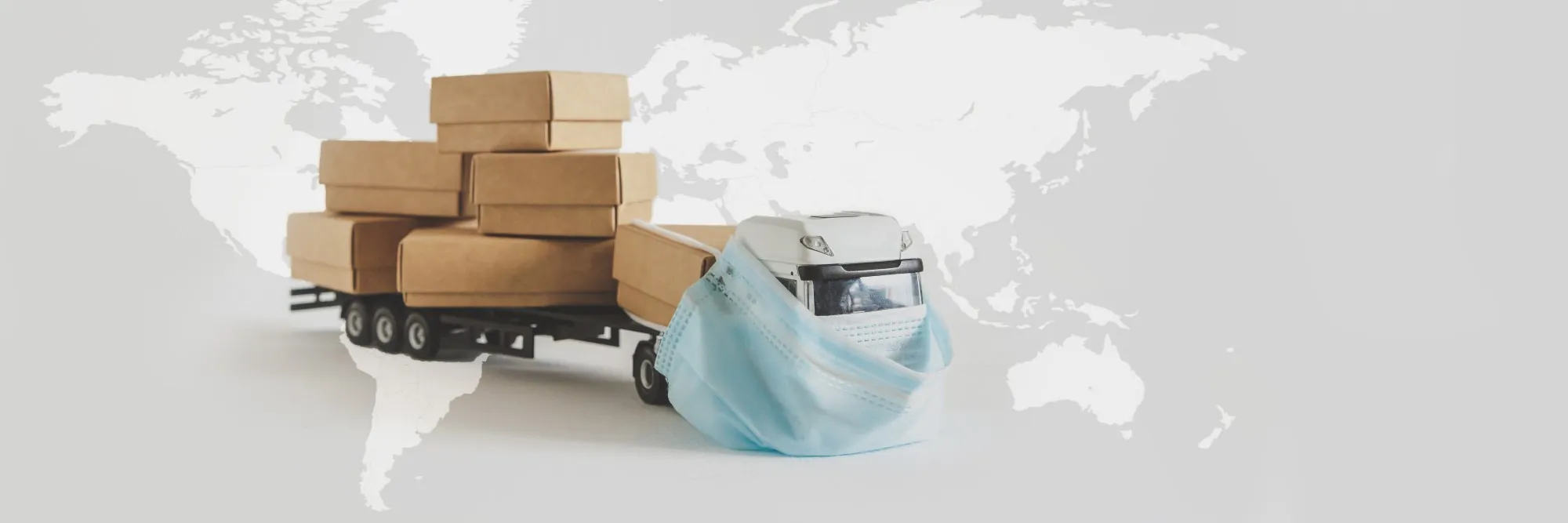 freight-shipping-during-coronavirus-toy-truck-wearing-mask-in-front-of-world-map