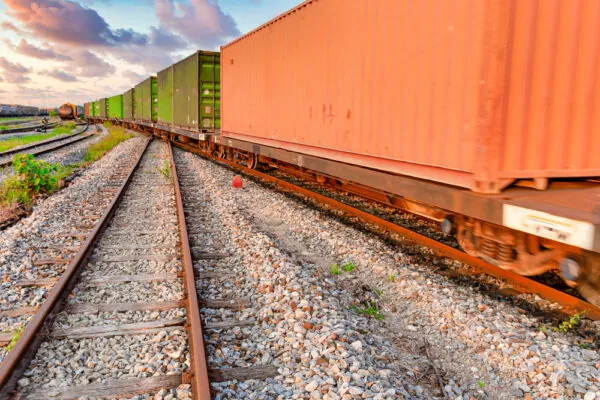 orange and green rail cars on railroad tracks