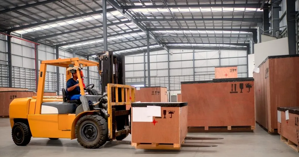 forklift in a warehouse lifting a wooden crate