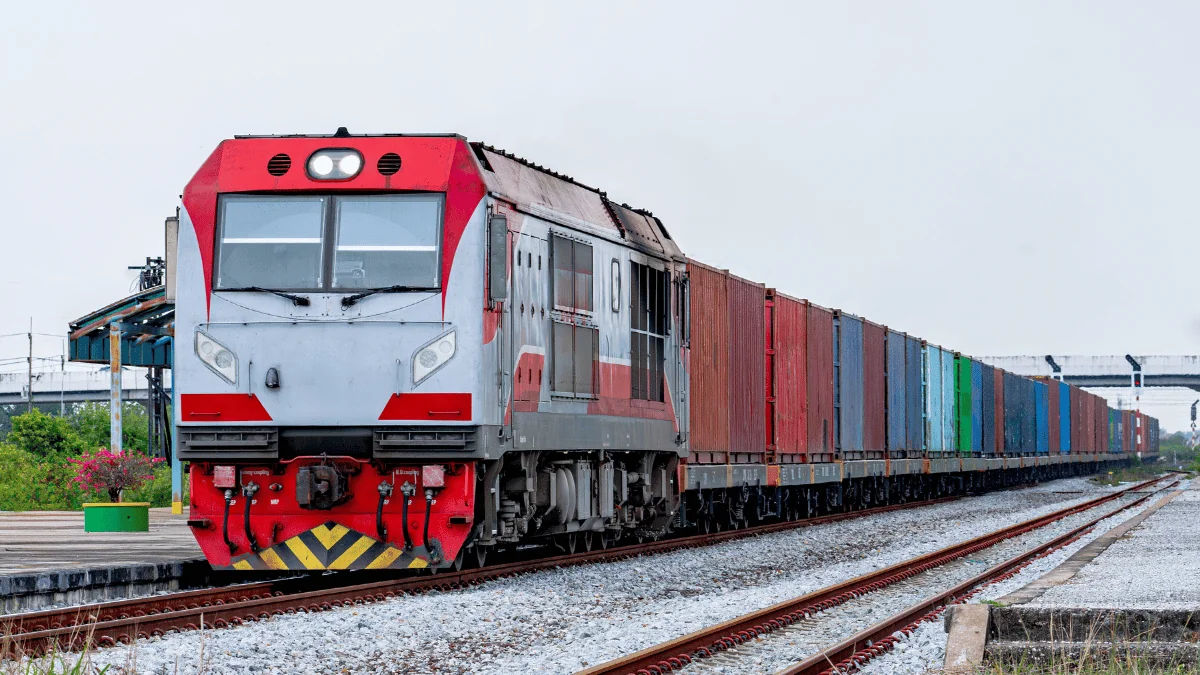 Become a Carrier freight train pulling container cars on rail line on cloudy day