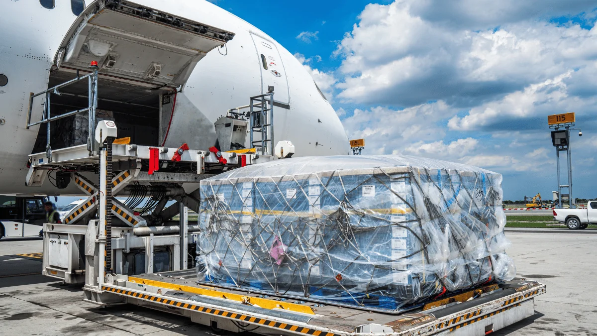 Become a Carrier palletized freight being loaded up onto a cargo airplane during the day