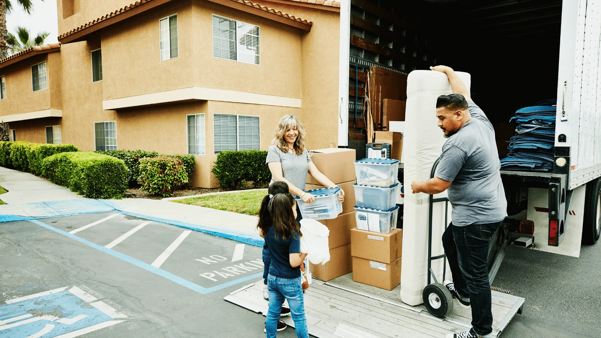 family with children loading boxes and mattress onto liftgate