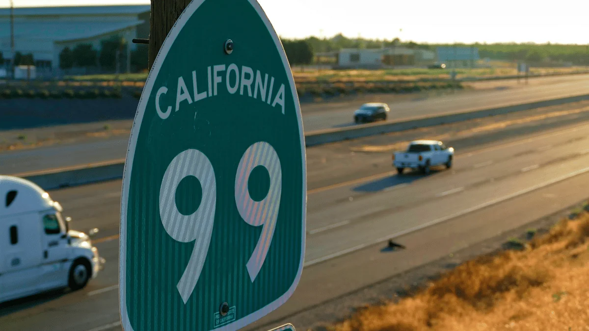 Modesto Freight Shipping green California State Route 99 sign with highway in the background