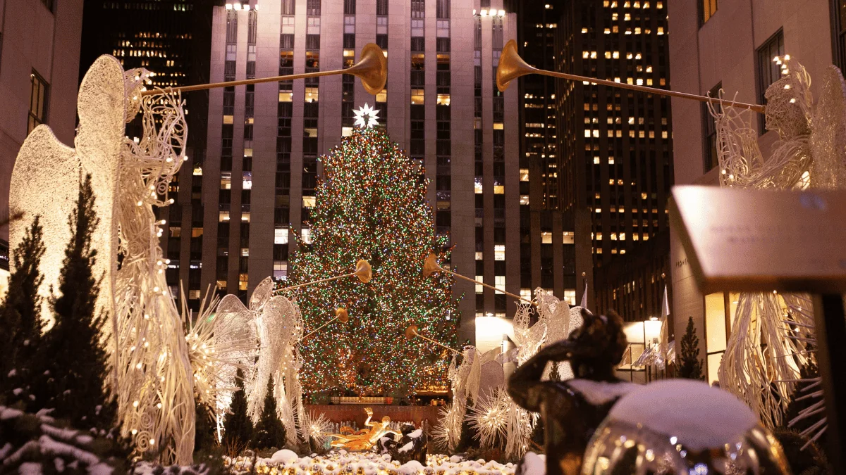 Rockefeller Christmas tree standing tall above beautiful trumpeting angel statues.