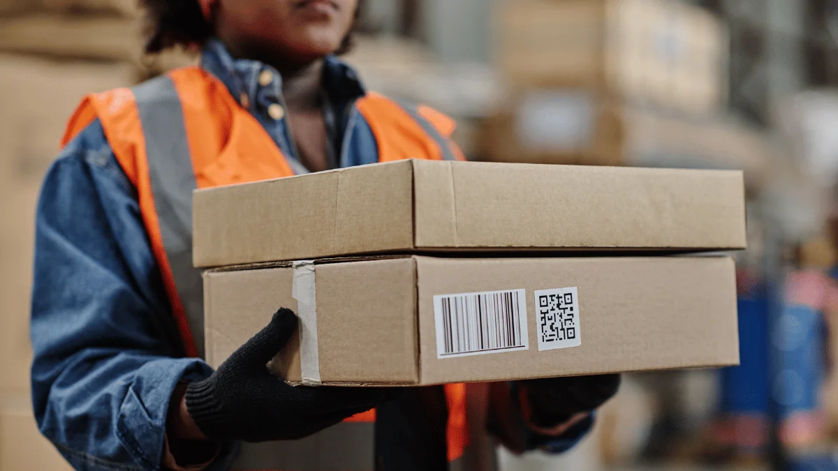 What Is FBA warehouse worker holding small rectangular boxes with gloved hands