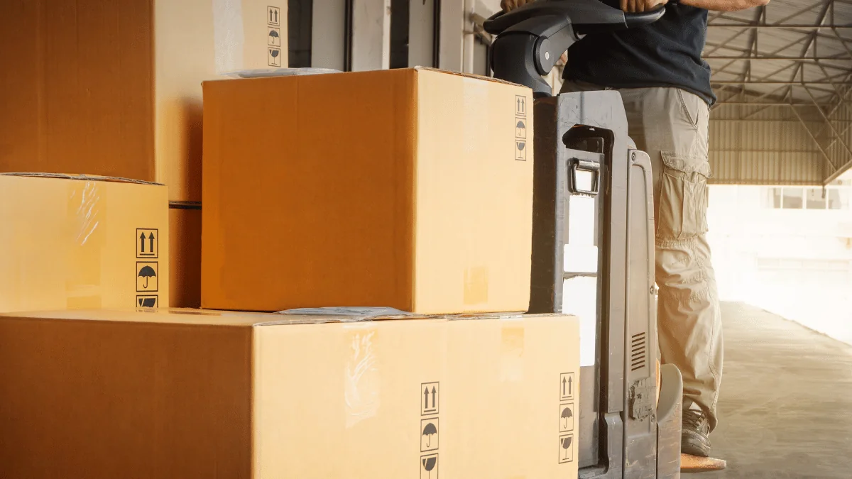 What Is Freight boxes on a pallet being moved by pallet jack by a warehouse worker