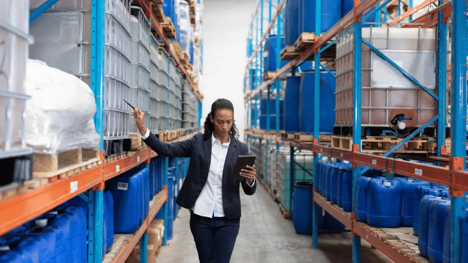 Freight Management Companies female manager pointing to palletized items on shelf in a warehouse aisle