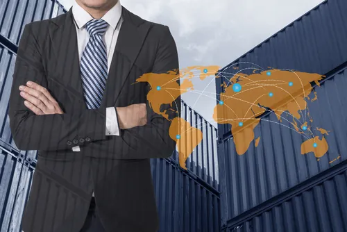 Customs clearance businessman crossing arms in front of shipping containers with a map of the world next to him