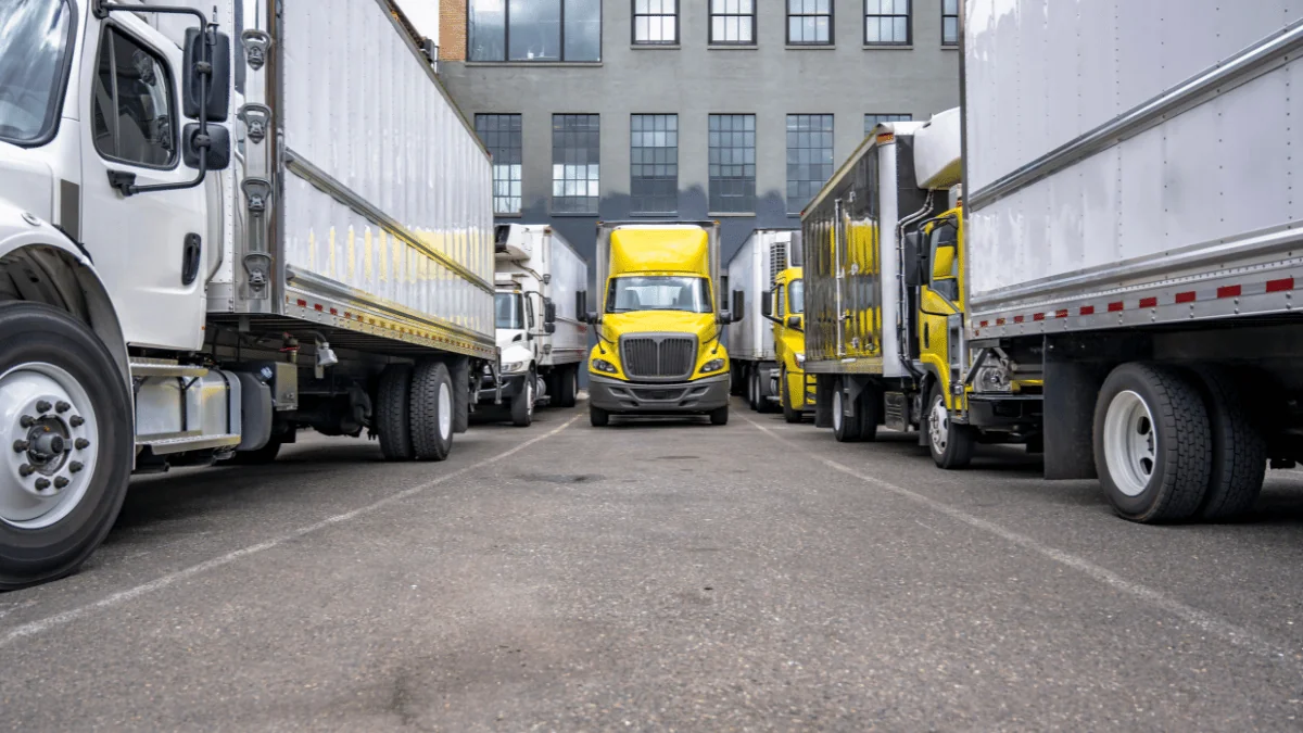 Dedicated Fleet Services yellow and white semi trucks parked in front of industrial building