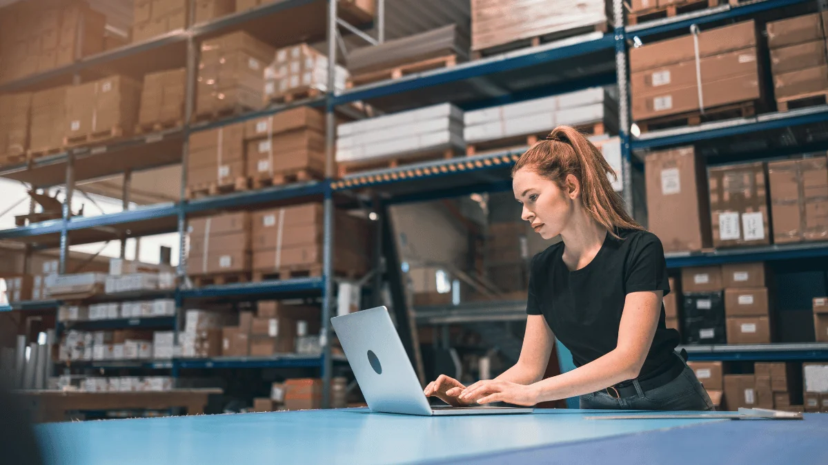 female employee on laptop in manufacturing warehouse facility