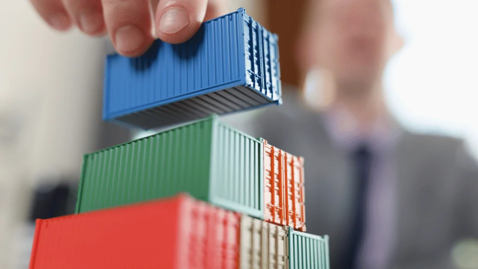 Reducing Freight Costs for Enterprises businessman stacking toy shipping containers