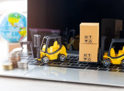 two yellow toy forklifts sitting on a laptops keyboard