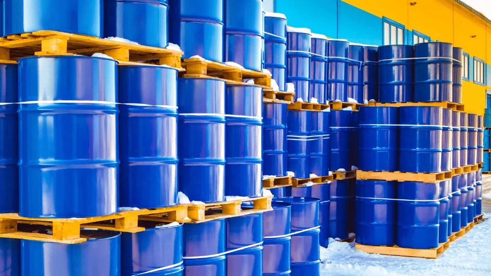 Shipping Chemicals and Hazardous Materials stacks of barrels on pallets outside in the snow next to chemical plant