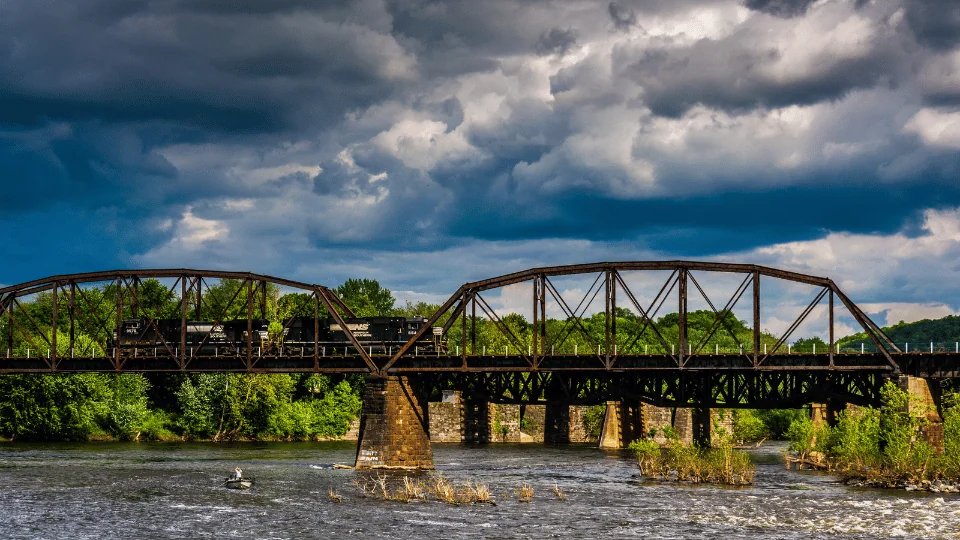 black freight rail trail on brown bridge over Delaware River