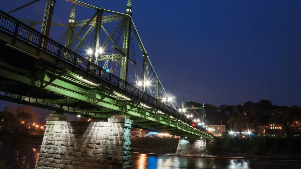 green bridge lit up at night over Delaware River