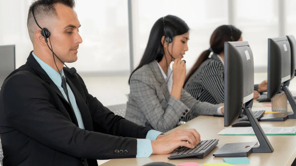 freight brokers wearing headsets working on computers while talking to clients