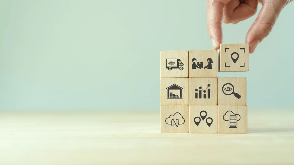 Outsourced Logistics for Enterprises hand stacking wooden blocks with icons symbolizing the principles of logistics management into a square