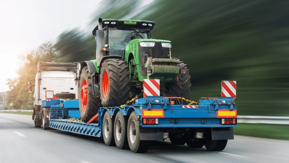 tractor strapped onto moving flatbed trailer